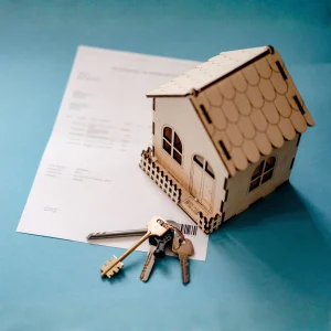 Modellino di casa in legno con chiavi su un contratto di mutuo