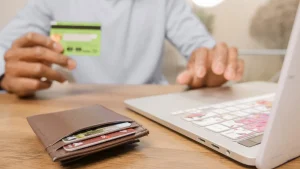 Persona con carta di credito in mano davanti al laptop durante la valutazione del merito creditizio per un mutuo